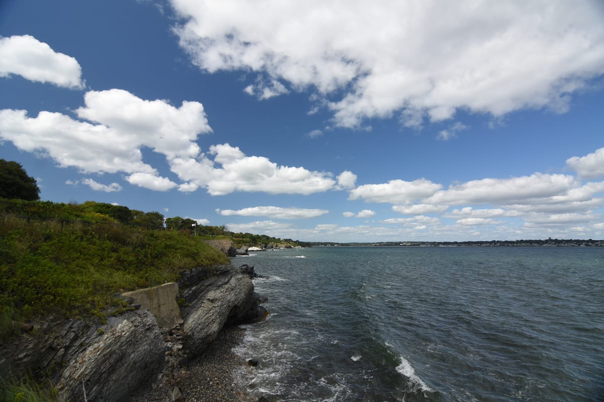 Coastal cliffs and bay under bright clouds